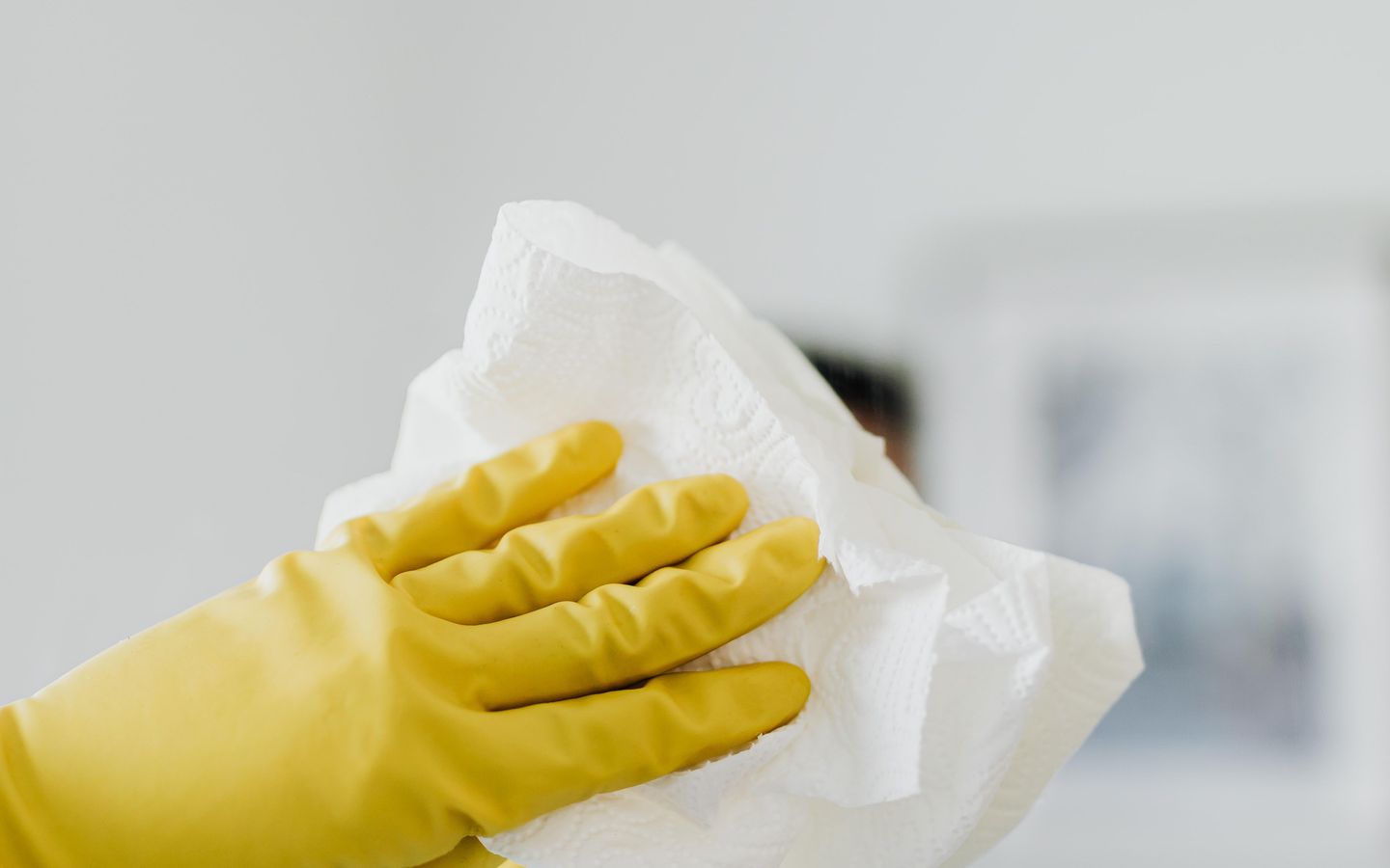 A gloved hand wiping down a surface with a cloth.