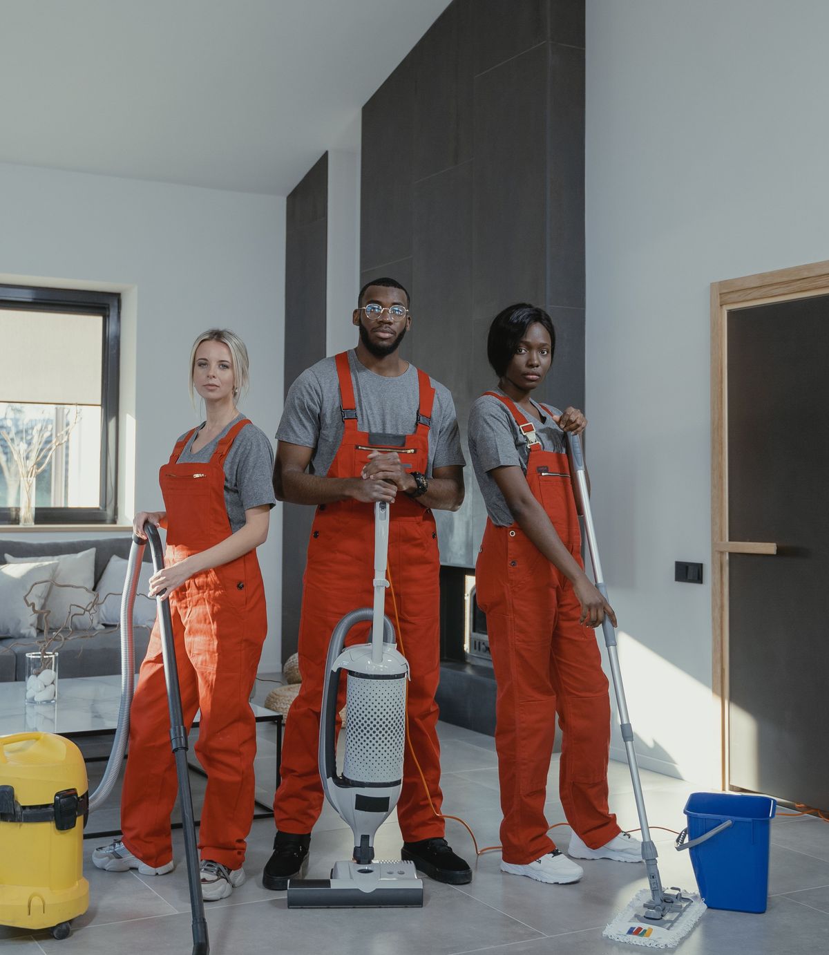 Three Marlbrook operatives in matching uniform with a vacuum, a flat mop and a bucket, standing in a breakout area.